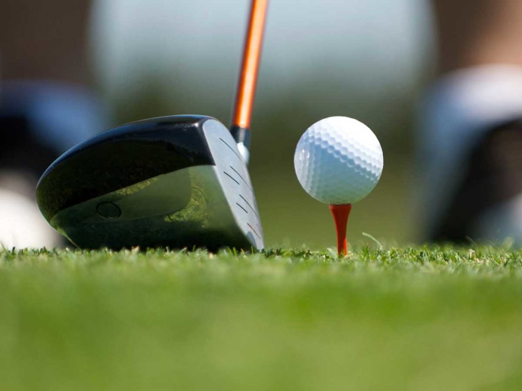 A golf club about to hit a golf ball.