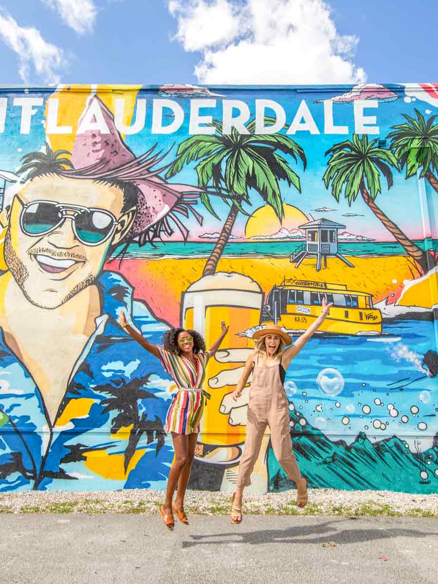 Girls jumping in front of a mural.