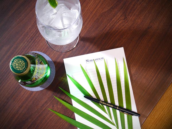 A notepad, pen, palm branch, and sparkling water.