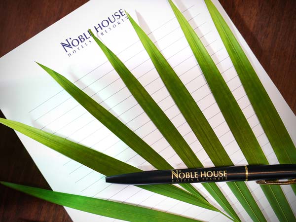 Palm tree leaf, pen, and Noblehouse notepad.