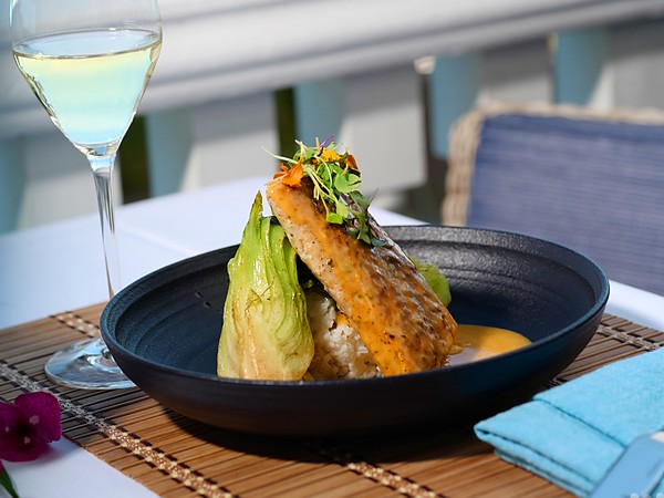 Pan-seared fish entrée with baby bok choy, jasmine rice, and microgreens served with white wine on the oceanfront dining terrace at Pelican Grand Beach Resort in Fort Lauderdale, Florida